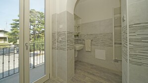 Une salle de bain moderne dotée d’une grande fenêtre, d’un lavabo et d’un espace douche.
