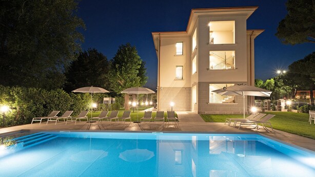 Un bâtiment moderne doté d’une piscine, de chaises longues et de parasols.