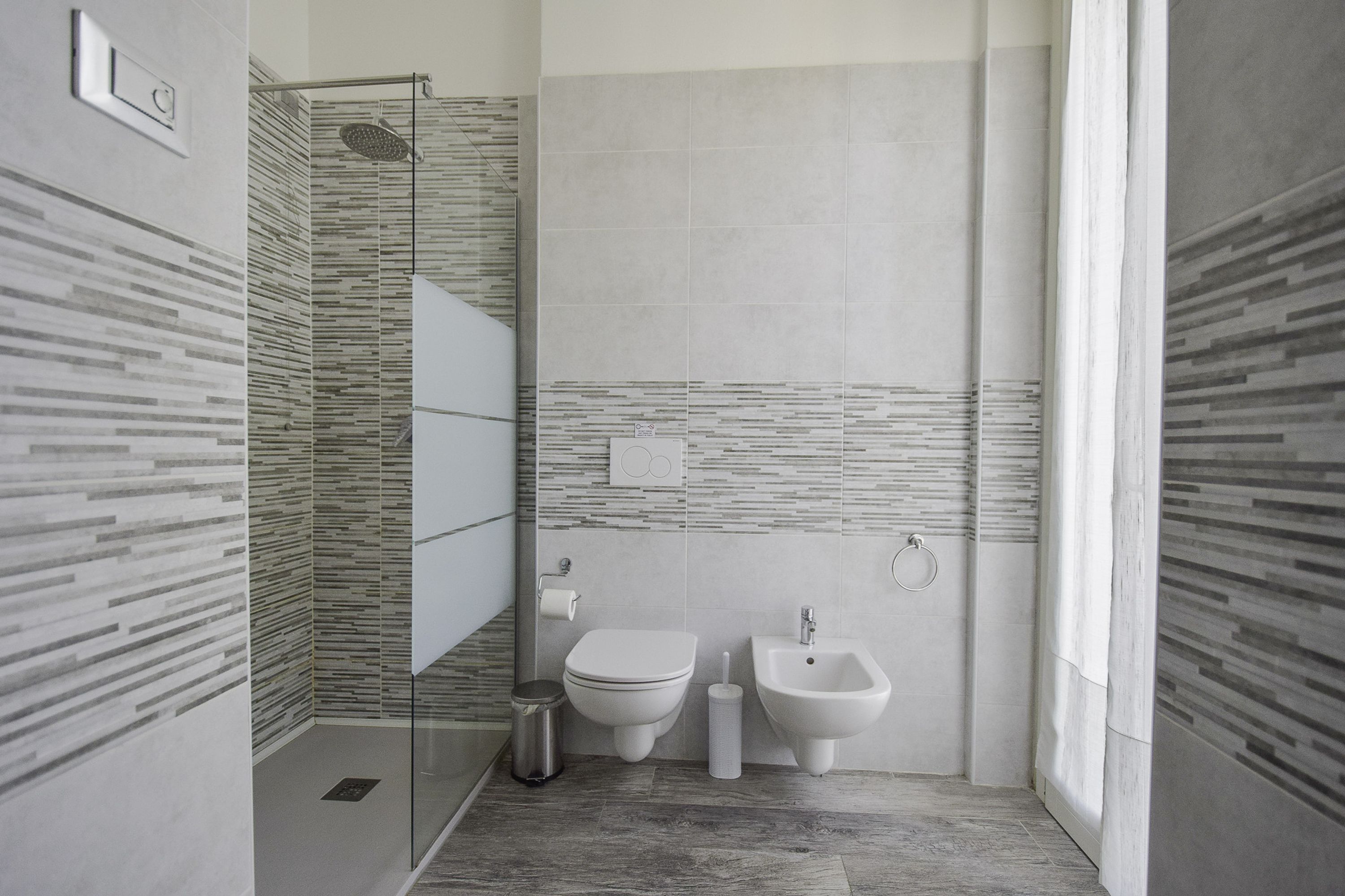 Une salle de bain moderne avec une douche à parois de verre, des toilettes, un bidet et un porte-rouleau de papier toilette.