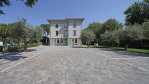 Un bâtiment à la façade symétrique, doté de nombreuses fenêtres et d’une cour dallée.