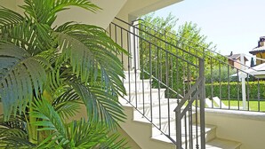Un escalier avec une rampe en métal, entouré de verdure et offrant une vue sur une maison.