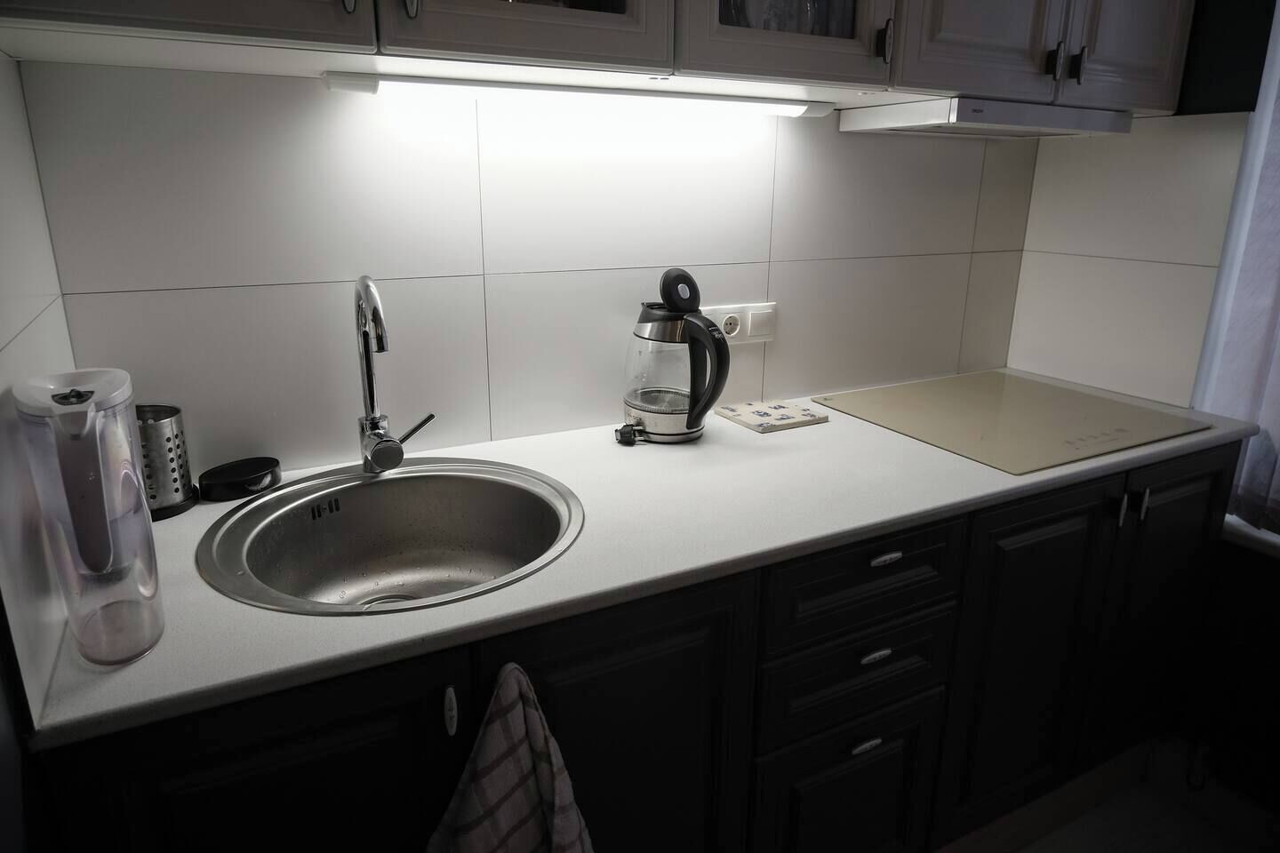 A modern kitchen with a stainless steel sink, a kettle, and a coffee maker.