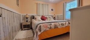 Een slaapkamer met een bed, nachtkastjes, een raam met gordijnen en een wandlamp.