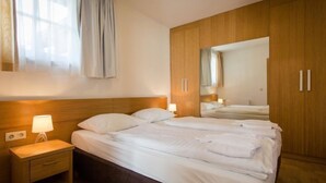 A hotel room with a large bed, wooden wardrobe, bedside lamps, and a window with curtains. - #11 mit Balkon by Interhome (Turracher Höhe)