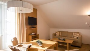 A modern living room with a wooden dining table, a sofa, and a television mounted on the wall. - #11 mit Balkon by Interhome (Turracher Höhe)