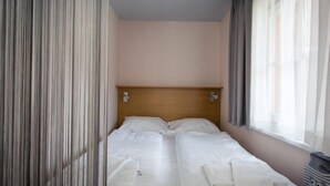 A hotel room with two single beds, a wooden headboard, a nightstand with a lamp, and sheer curtains. - Studio #4 mit Balkon by Interhome (Turracher Höhe)
