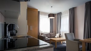 A modern hotel room with a kitchen area, a sofa, a dining table, and a chair. - Studio #4 mit Balkon by Interhome (Turracher Höhe)