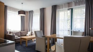 A modern hotel room with a sofa, dining table, chairs, and a large window with curtains. - Studio #4 mit Balkon by Interhome (Turracher Höhe)