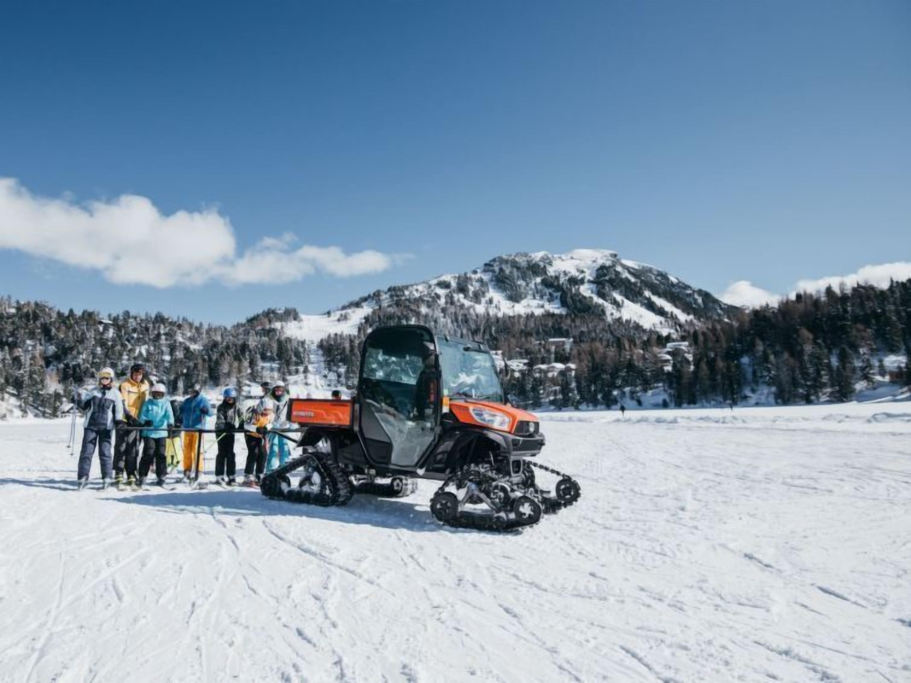 A group of people standing in a snowy field with a snowmobile in the foreground.