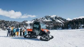 A group of people standing in a snowy field with a snowmobile in the foreground.