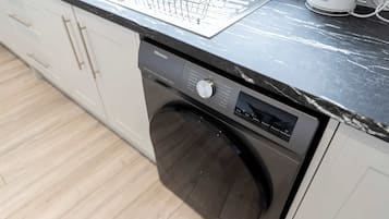 A modern kitchen with a built-in dishwasher, a stainless steel sink, and a coffee maker.
