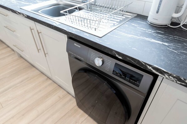 A modern kitchen with a built-in dishwasher, a stainless steel sink, and a coffee maker.