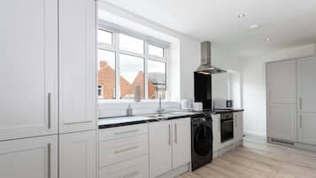 A modern kitchen with white cabinetry, a built-in oven, and a window overlooking a brick building.