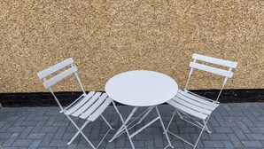 A metal table and two chairs with a textured wall in the background. - Stylish 3 Bed House With TVs in Each Bedroom (Darlington)