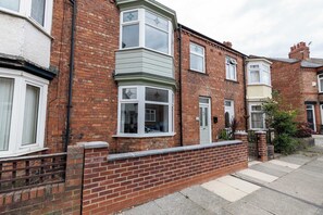 A row of terraced houses with brick facades, bay windows, and a gated entrance. - Stylish 3 Bed House With TVs in Each Bedroom (Darlington)