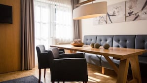 A modern living room with a wooden dining table, black chairs, a blue sofa, and a large painting on the wall.