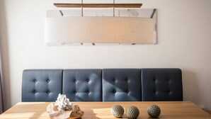 A dining area with a wooden table, a blue upholstered bench, and decorative objects on the table.