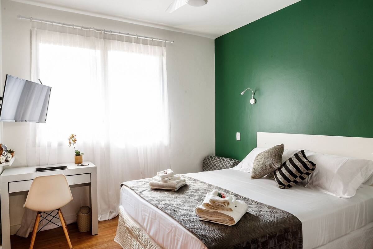 A neatly arranged bedroom with a bed, a desk, and a chair.