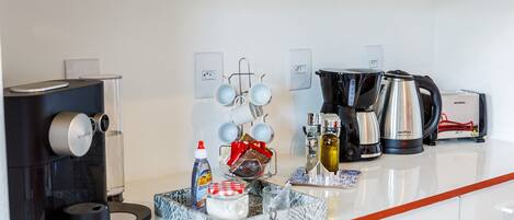 Una cocina moderna equipada con cafetera, hervidor y diferentes utensilios de cocina.