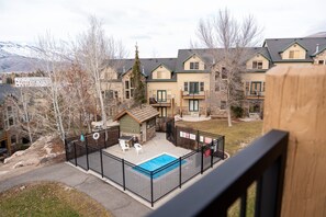 Ein Wohngebiet mit einem eingezäunten Garten, einem kleinen Pool und einer Holzterrasse.
