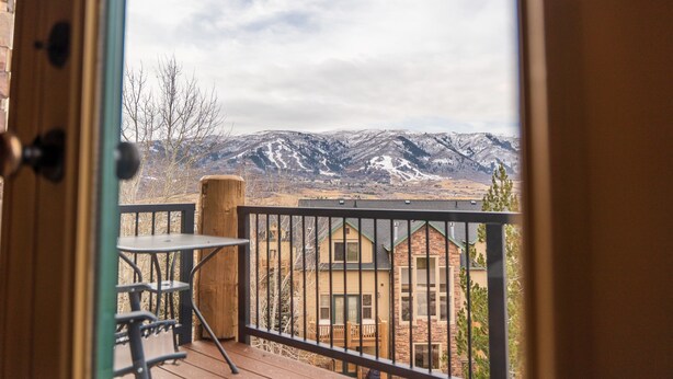 Ein Balkon mit Blick auf schneebedeckte Berge, einer Holzterrasse und einem Tisch mit Stühlen.