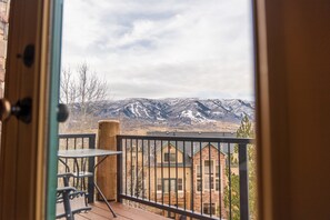 Ein Balkon mit Blick auf schneebedeckte Berge, einer Holzterrasse und einem Tisch mit Stühlen.