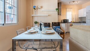 Une cuisine moderne avec des meubles blancs, un four à micro-ondes et un coin repas doté d’une table en verre, mise pour deux personnes.