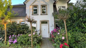 A two-story house with a white facade, a dark roof, and a front entrance. - Schöne Ferienwohnung für Geschäftsleute und Paare (Osnabrück)