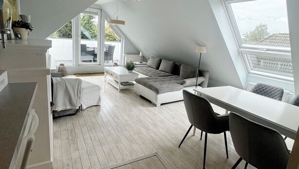A modern loft bedroom with a sloped ceiling, a large skylight, a dining area, and a cozy seating area. - Schöne Ferienwohnung für Geschäftsleute und Paare (Osnabrück)