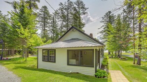 A small, single-story house with a gabled roof, large windows, and a front porch. - Beach & Kayaks: Waterfront Cabin on Lake Pleasant! (Speculator)