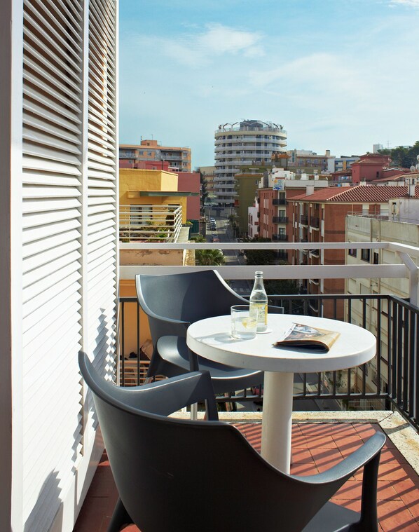 A balcony with a round table and two chairs, overlooking a cityscape with various buildings. - BLUESEA Copacabana (Lloret de Mar)