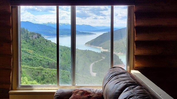 A room with a large window overlooking a mountainous landscape and a lake. - Classic log cabin with stunning views! (Irwin)
