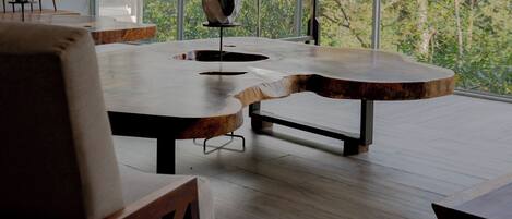Un interior moderno con un ventanal grande, muebles de madera y un florero con flores.