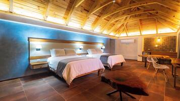 Un dormitorio con dos camas, techo de madera y un rincón comedor con una silla.