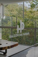 A modern interior with a large window, a wooden table, and a sign reading "BALCÓN DEL PARQUE".