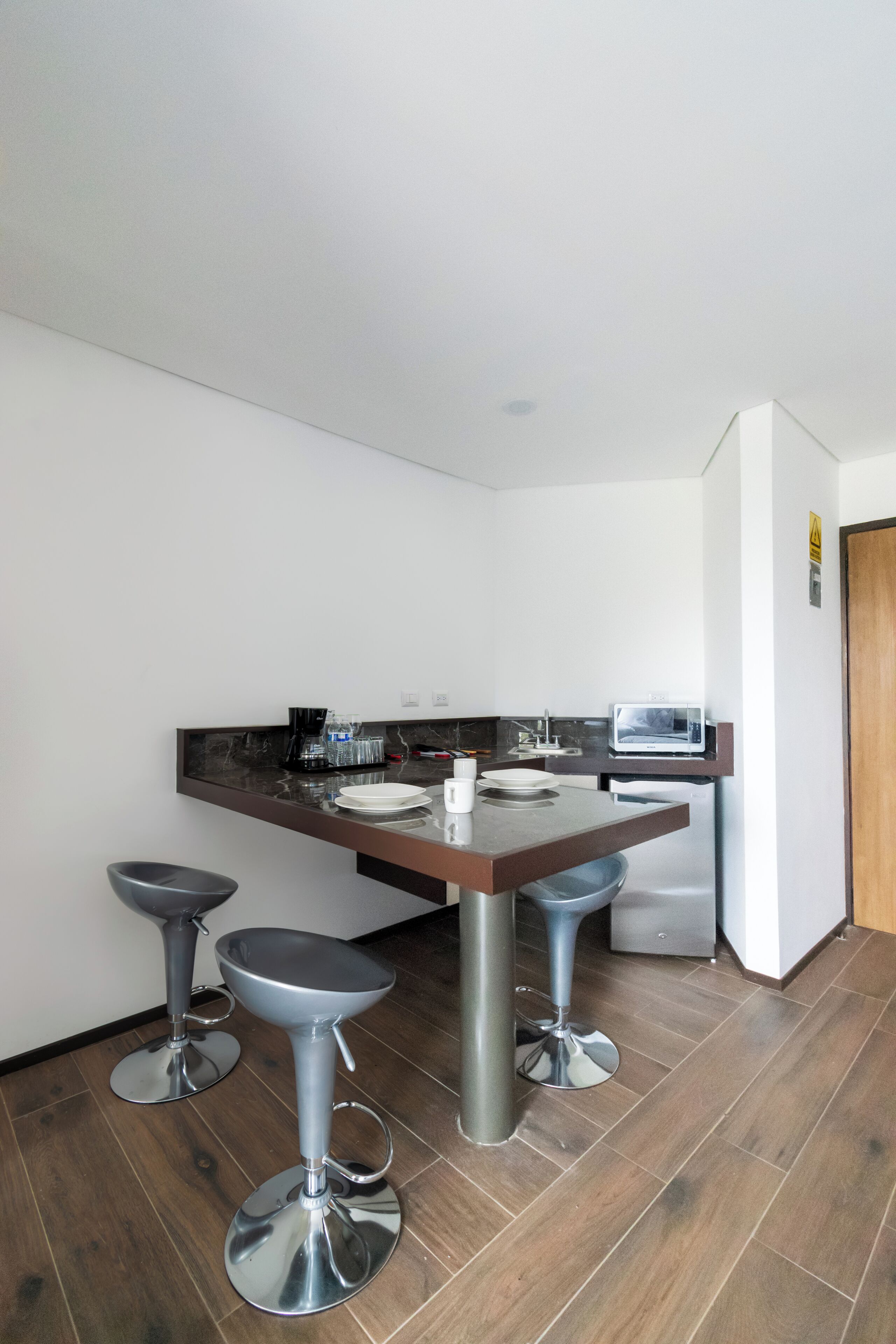 A modern kitchen with a dark countertop, stainless steel appliances, and two bar stools.