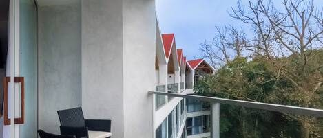 Un balcon au design moderne, doté d’une balustrade en verre et d’un espace salon comprenant deux chaises et une petite table.