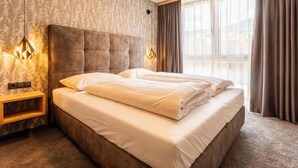 Habitación de hotel moderna con una cama grande, una mesita de noche, una lámpara de pared y vistas a la ciudad a través de amplios ventanales.