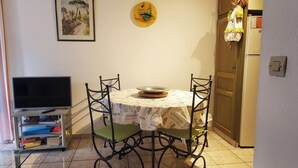 A dining area with a table, chairs, a television, and a refrigerator. - Centrally located apartment with swimming pool (Fréjus)