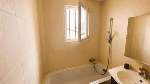 A bathroom with a bathtub, a shower, a sink, and a window. - Cosy Town house with its beautiful terrace (Deauville)