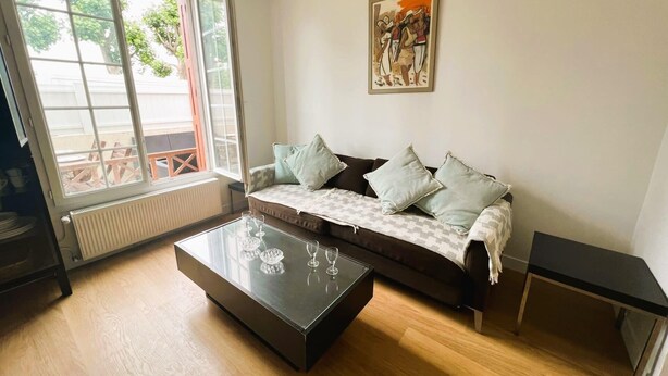 A living room with a sofa, a glass coffee table, and a painting on the wall. - Cosy Town house with its beautiful terrace (Deauville)