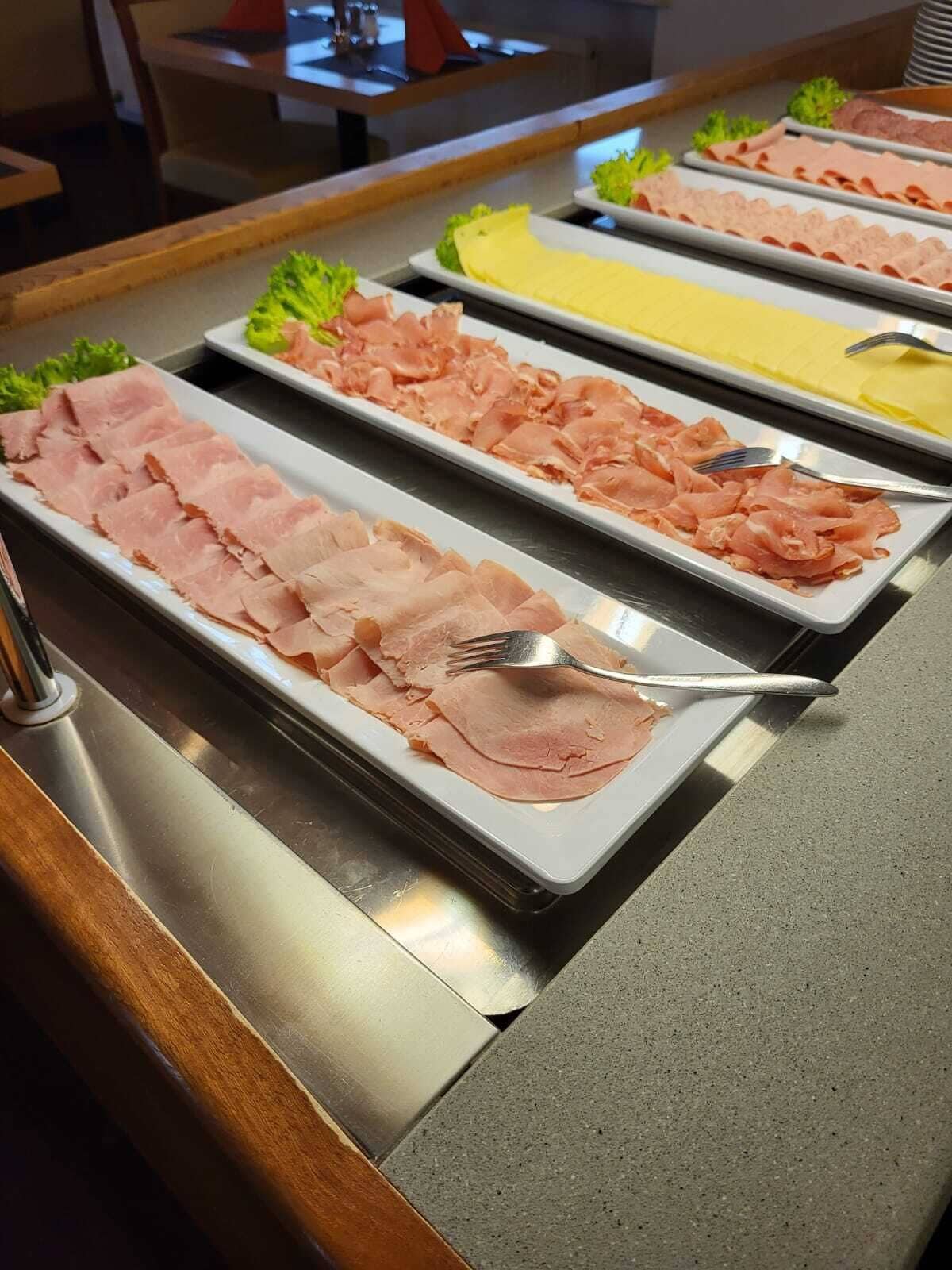Un bufé con diversos tipos de carne y un tenedor sobre una bandeja.