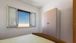 Een slaapkamer met een bed, een kledingkast en een raam met uitzicht op de lucht.