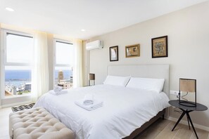 A hotel room with a large bed, a bedside table, a chair, and a view of the sea. - Home2Book Stylish Sea Views Studio Santa Cruz (Santa Cruz de Tenerife)