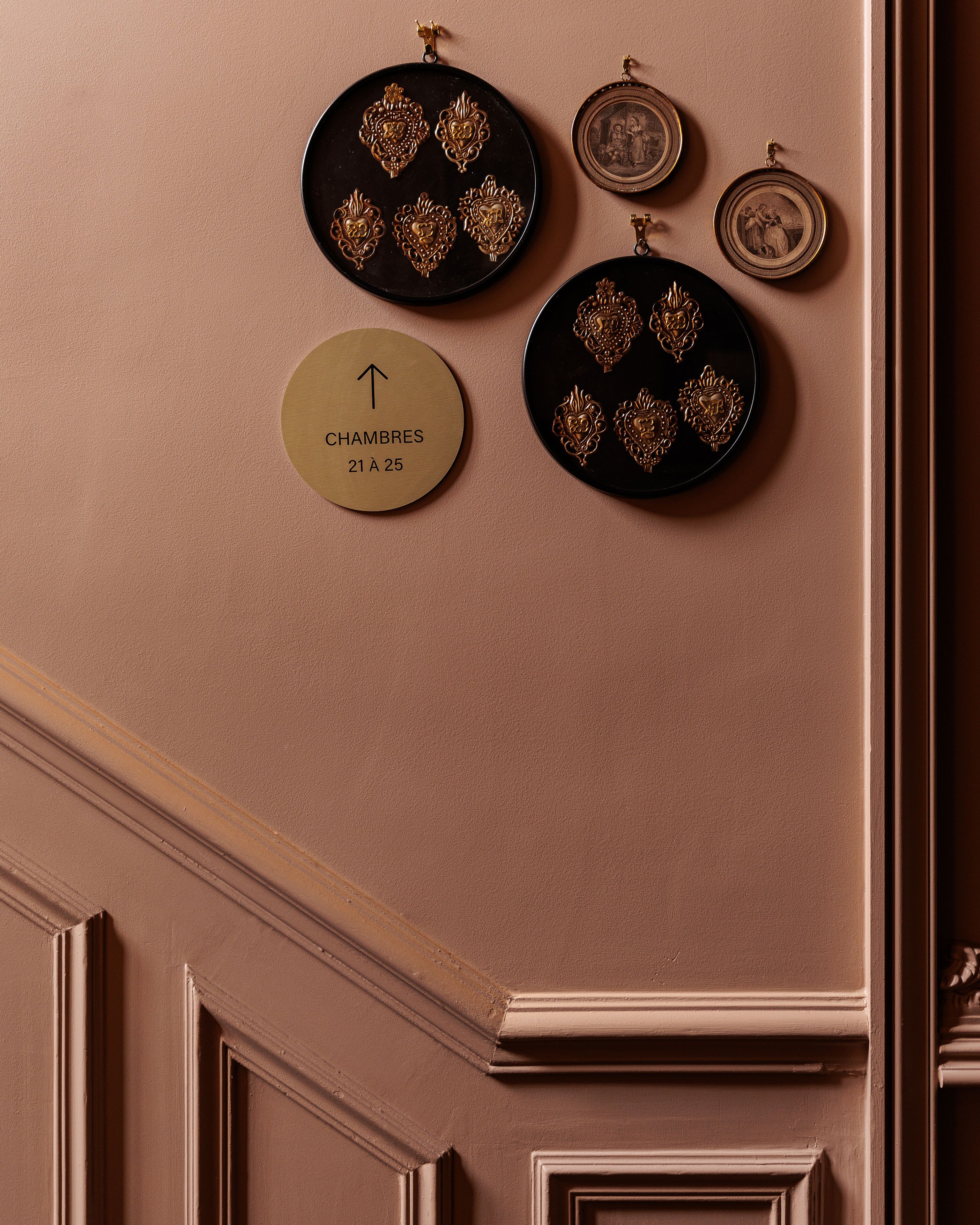 Un mur orné d’assiettes décoratives et d’une plaque indiquant les numéros des chambres, du 21 au 25.