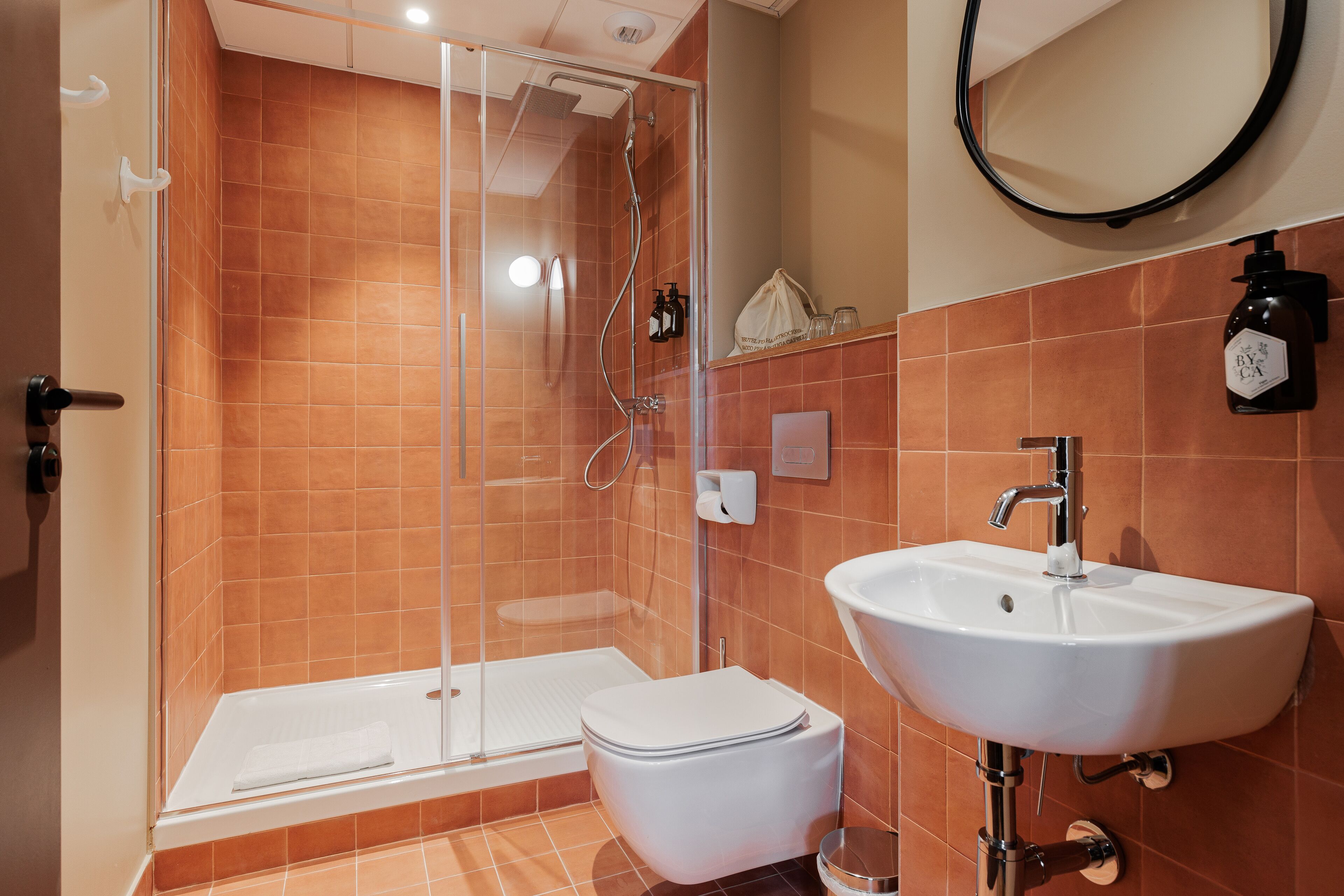 A modern bathroom with a glass-enclosed shower, a white sink, and a toilet.