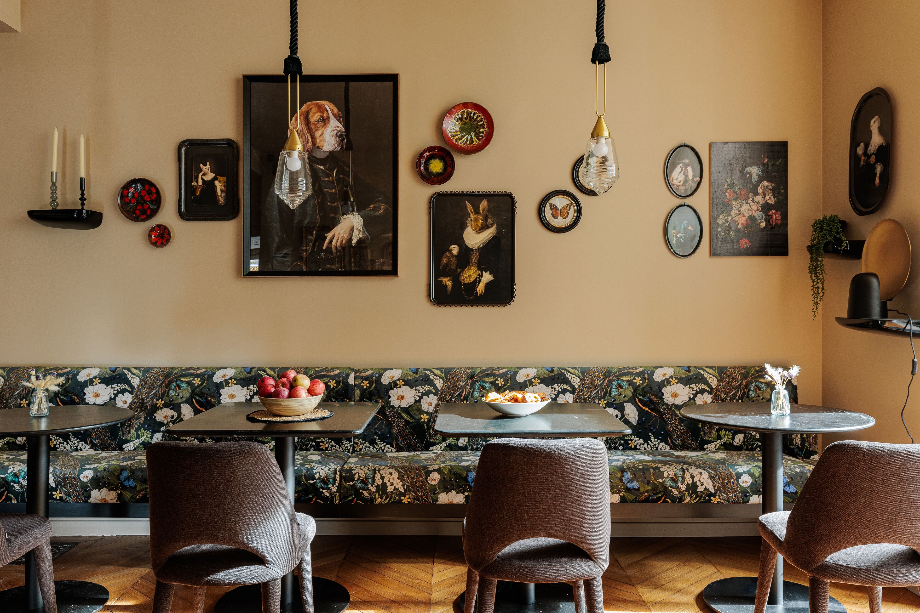 A dining area with a floral sofa, round tables, and brown chairs.