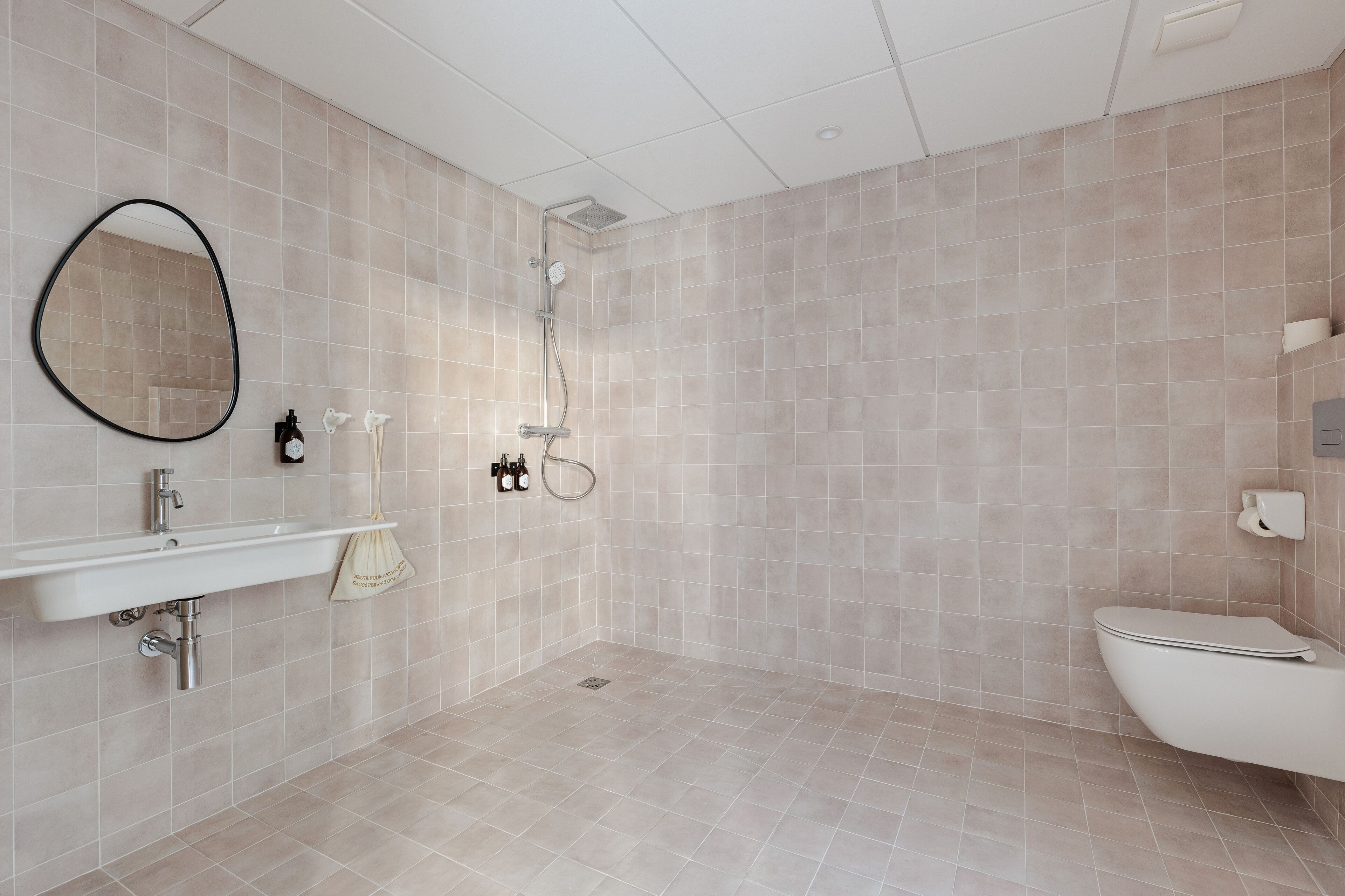 A modern bathroom with a sink, mirror, shower, and toilet.