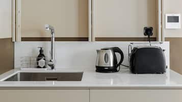 A kitchen with a sink, a kettle, a toaster, and a wall-mounted device.