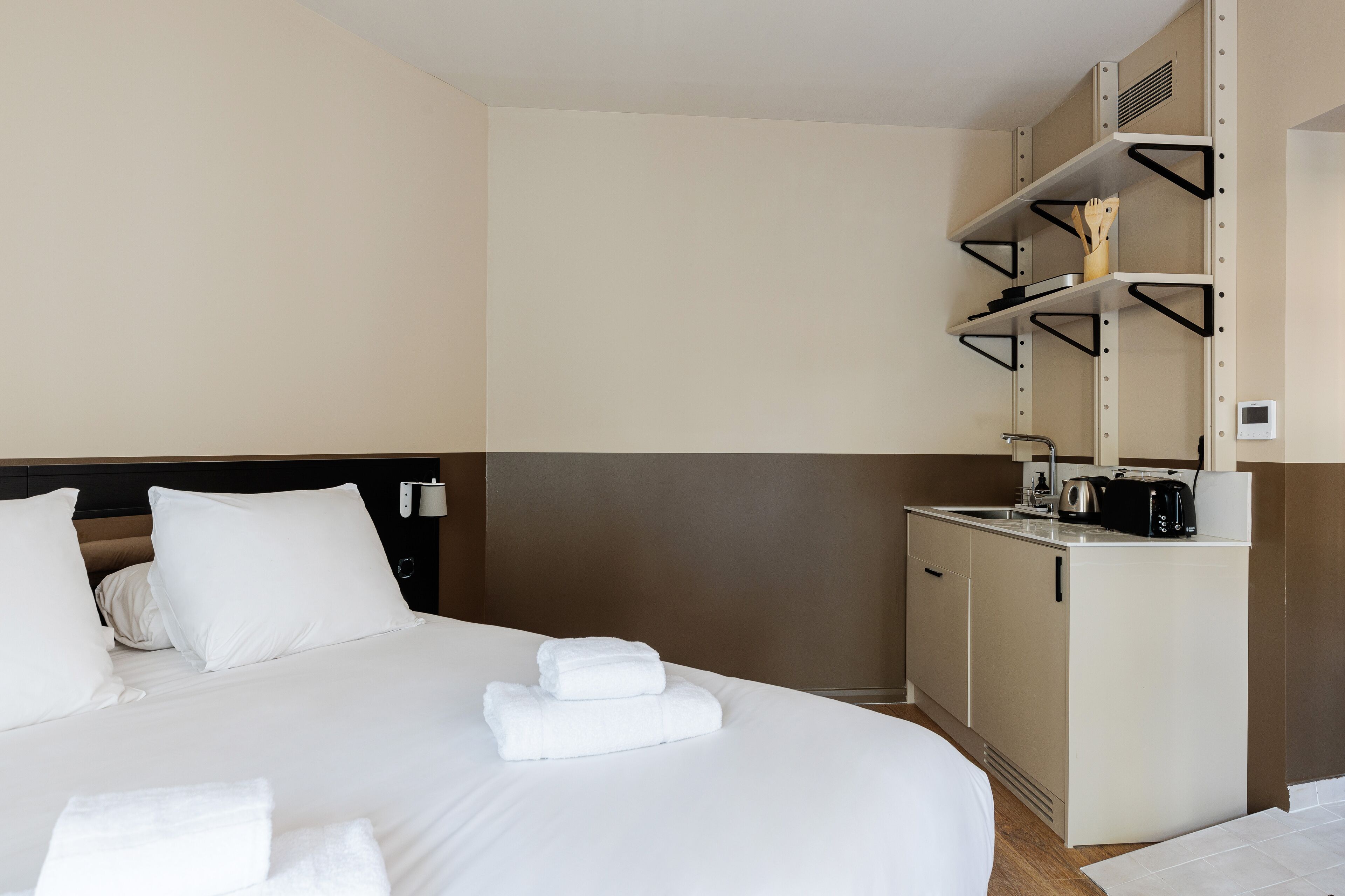Une chambre d’hôtel avec un lit, une petite kitchenette et une salle de bain.